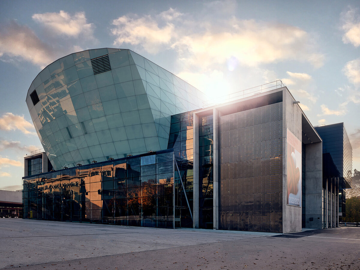 Moderne Glasfassade des Musiktheaters im Kulturbezirk St. Pölten bei Sonnenuntergang – Architekturfotografie mit stimmungsvoller Lichtführung und urbanem Kontext in Österreich.