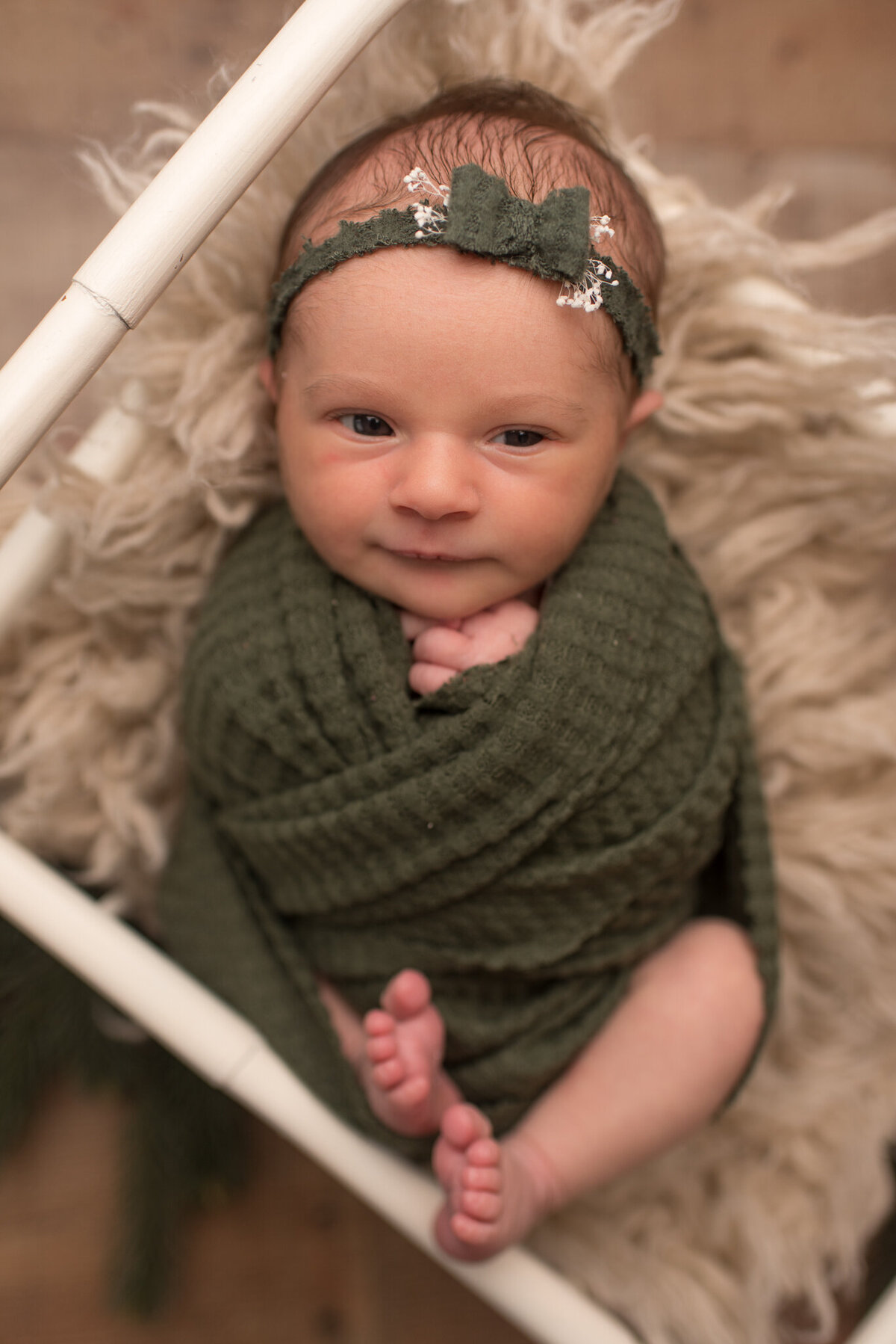 Baby girl wrapped in green wrap with green headband, green bow
