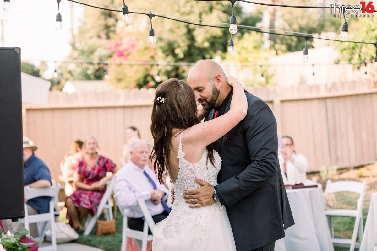 Bride and Groom share first dance together as guests look on