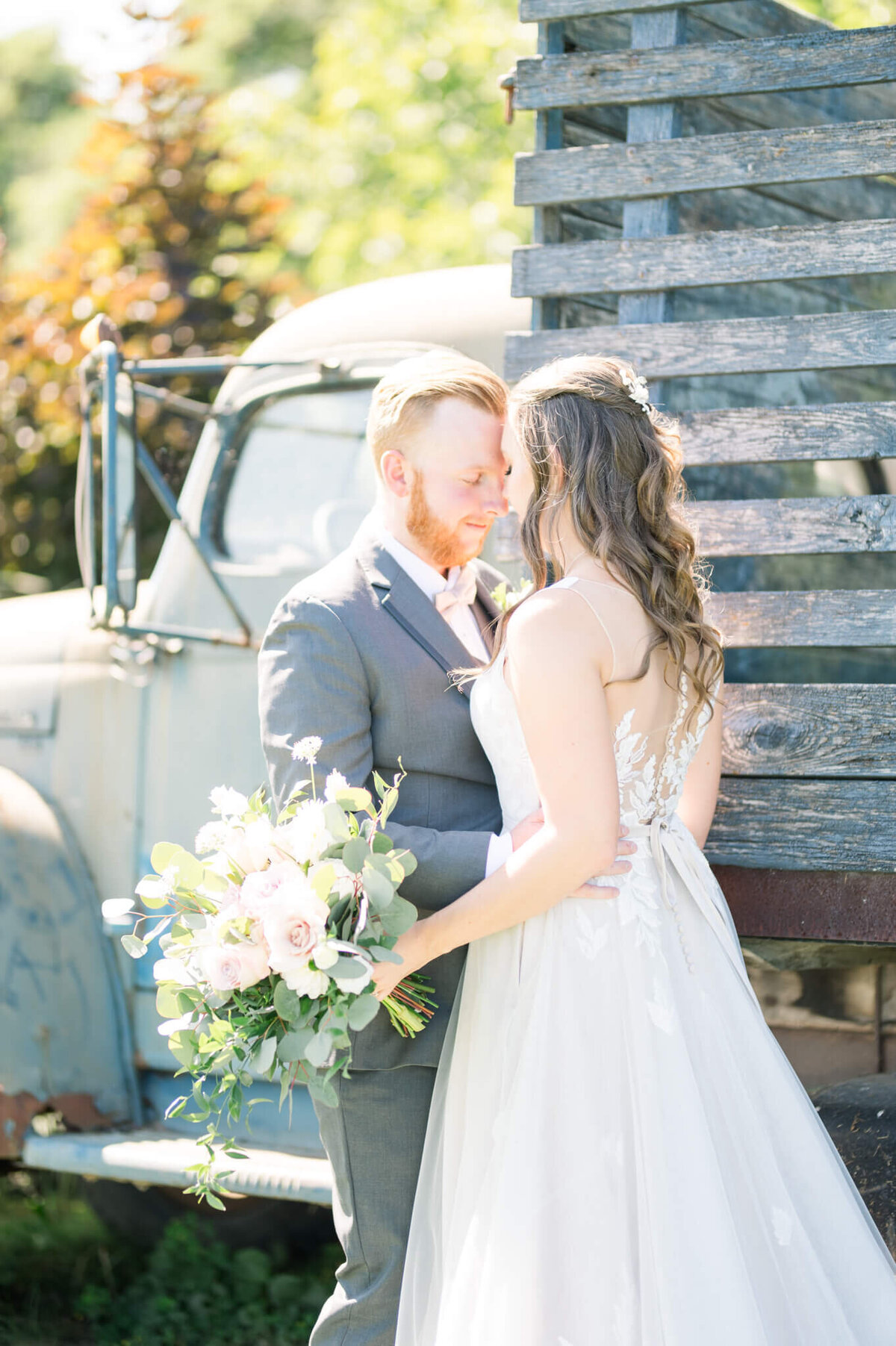 Bride and groom touching foreheads  in front of vintage truck