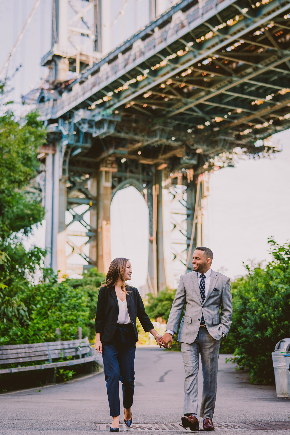 An engaged couple walking down washington street with the brooklyn bridge behind them