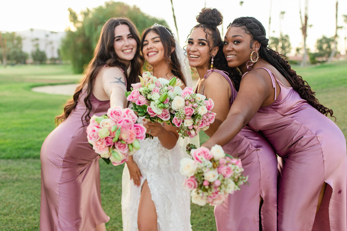 bride and bridesmaids point their bridal bouquets at the camera