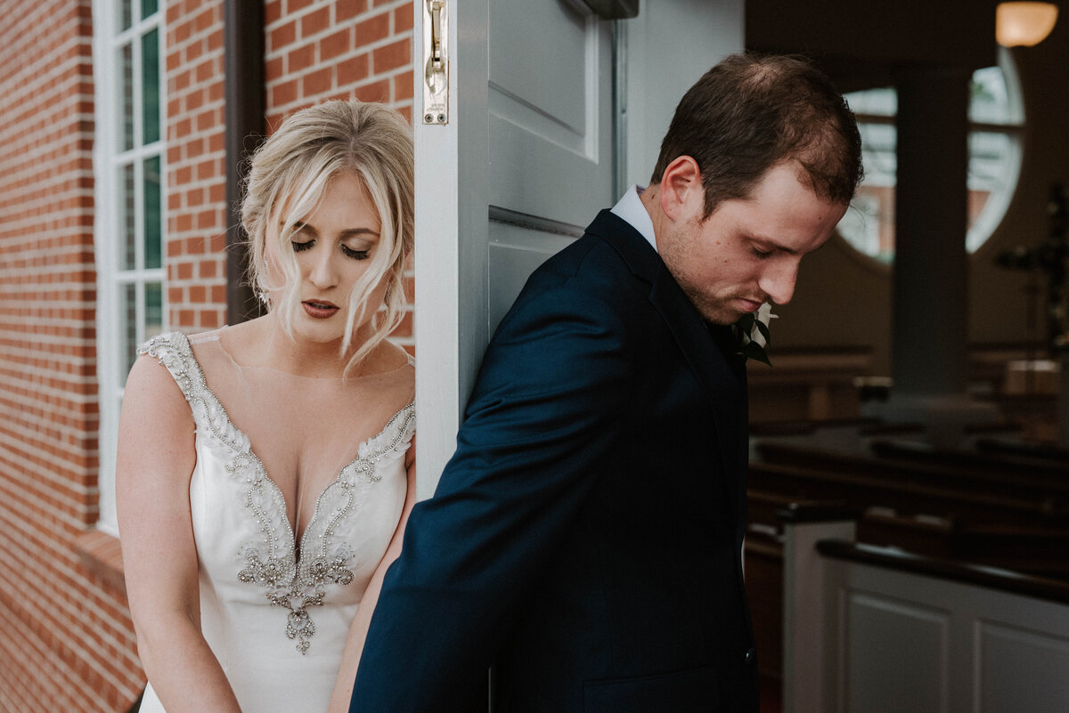 Bride and groom on either side of a door