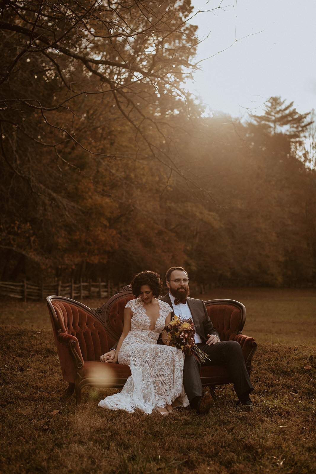wedding couple sitting on vintage red couch 
