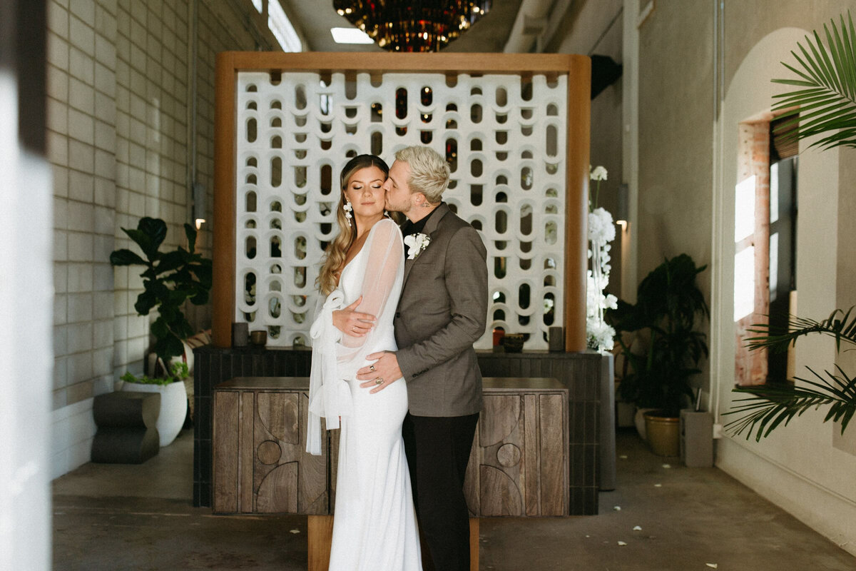 Bride and groom embracing at Fortuna’s Row wedding, a historical wedding venue with an industrial vibe in Calgary, featured on the Brontë Bride Vendor Guide.