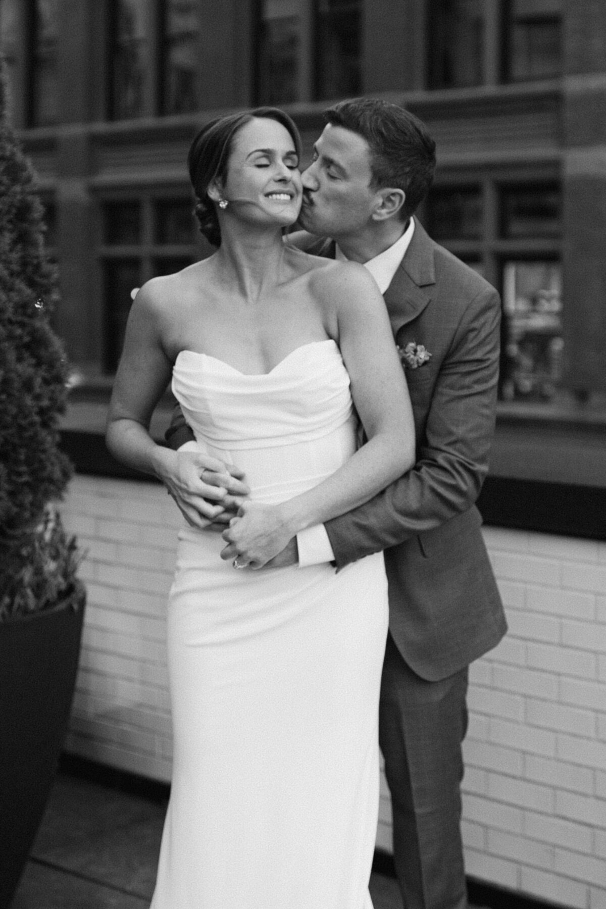 Bride and groom share tender moment in elegant black and white portrait.