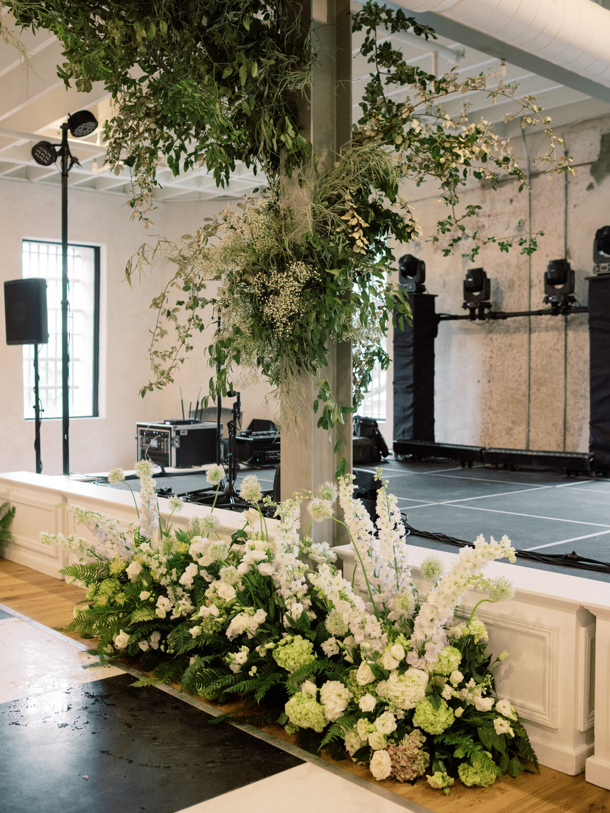 This image showcases a vibrant floral display gracefully positioned next to a beautifully arranged stage, ready for a lively wedding band.