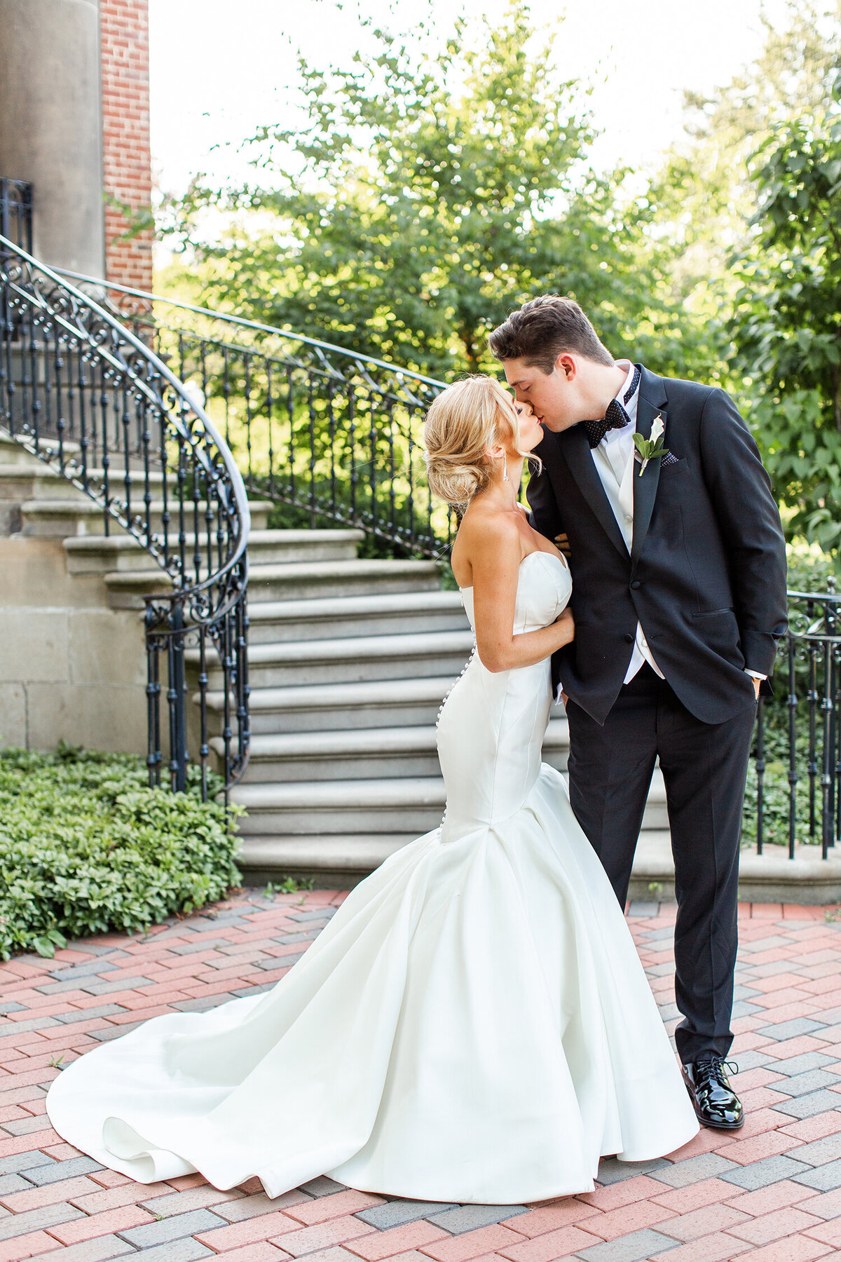 Bride and groom sharing a kiss in front of a grand staircase