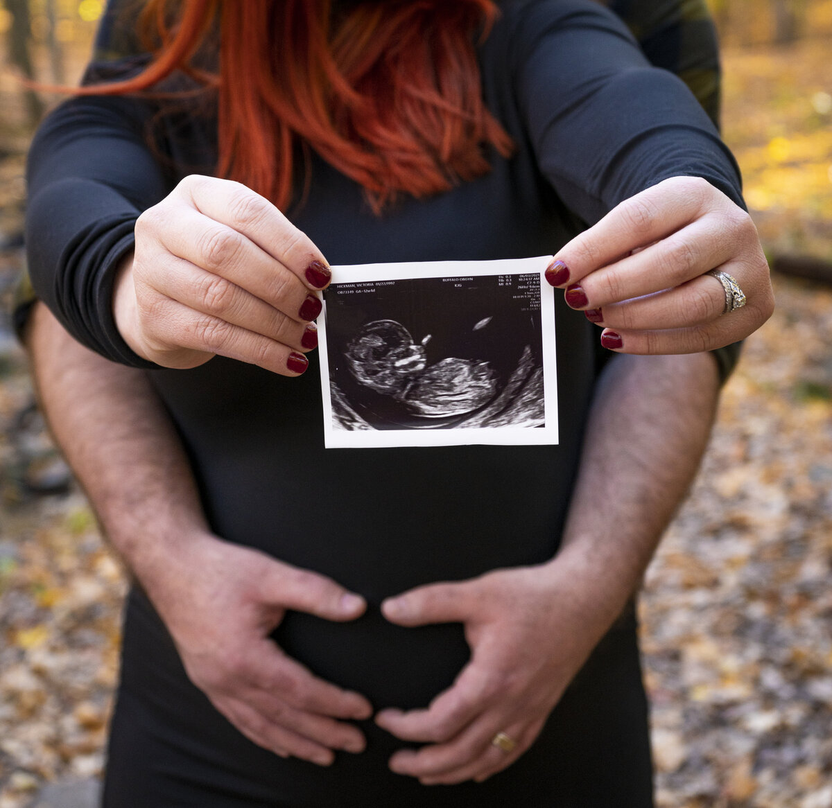 Maternity photo of a woman holding her baby's ultrasound photo