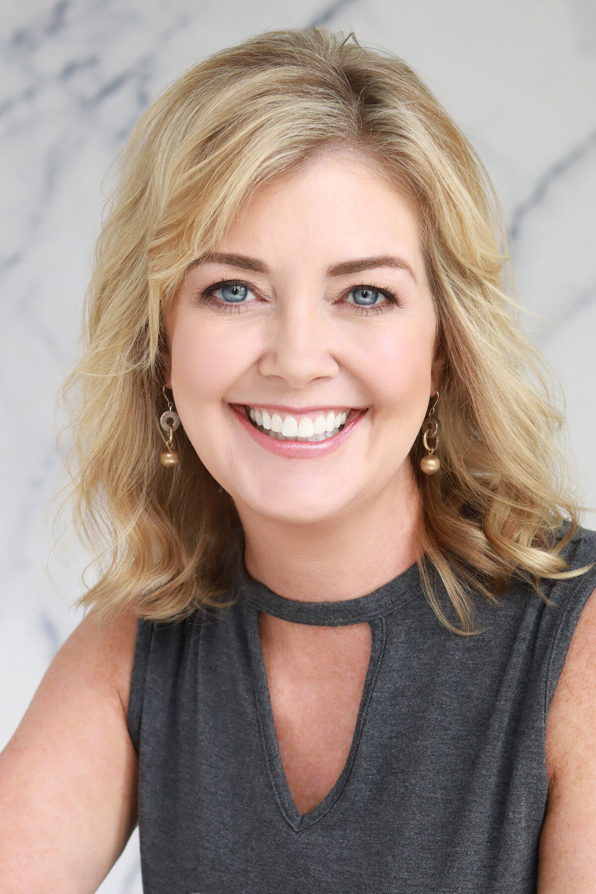 A woman smiling in front of a marble wall