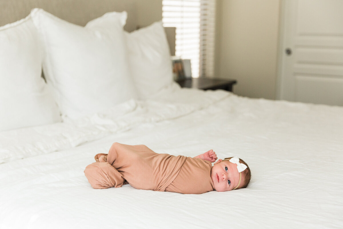 newborn baby sleeping on bed in lifestyle photography session