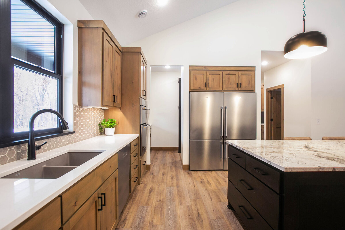 Open kitchen with dark cabinets, large island, and quartz countertops in an Elk River custom home