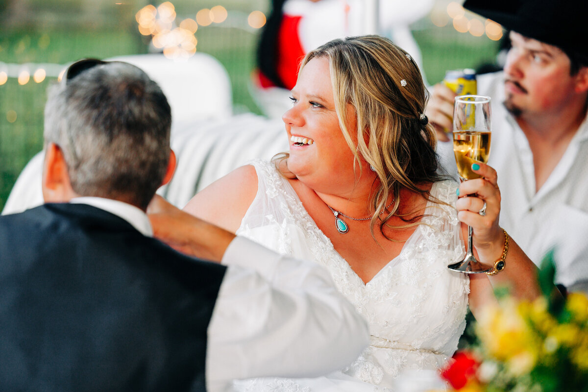 Bride smiling with champagne glass during wedding reception speeches