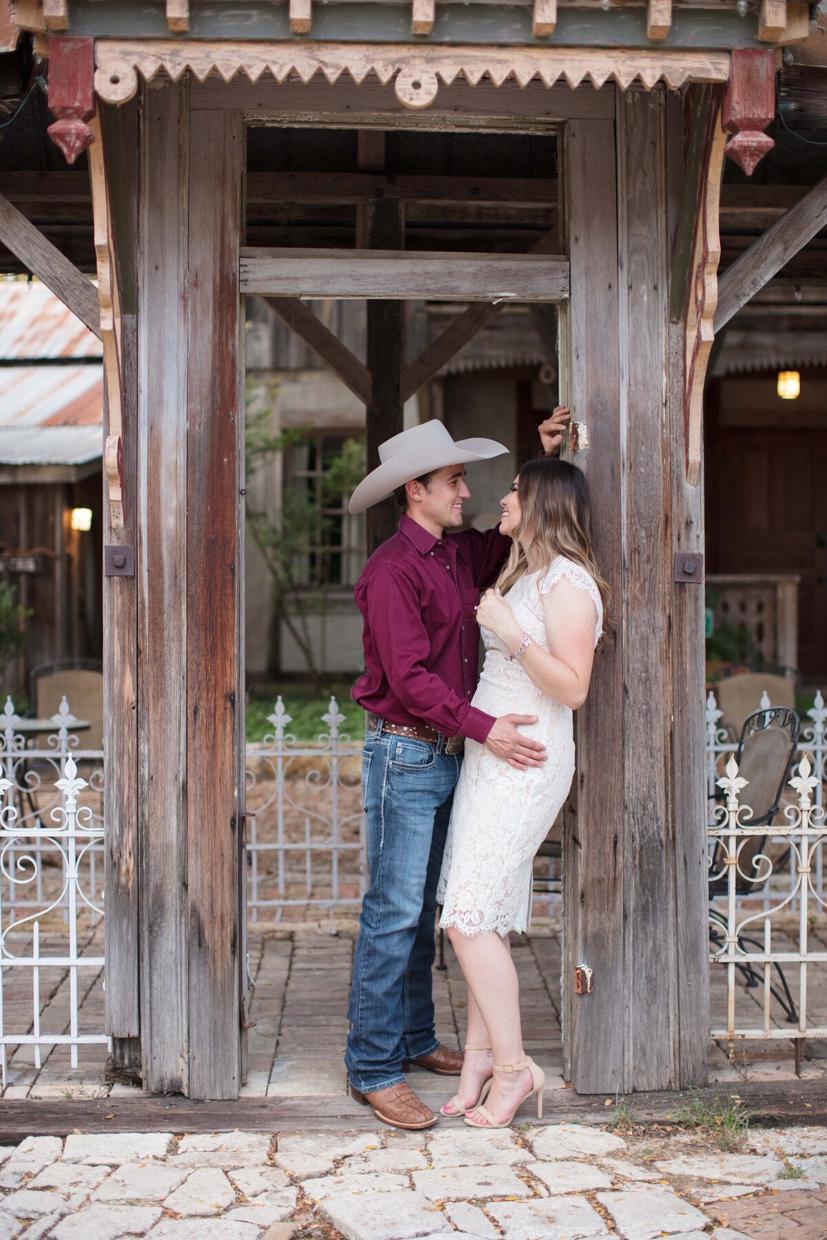 white dress and cowboy hat engagement session in Gruene New Braunfels Texas wood and iron rail hand on her hip Firefly Photography
