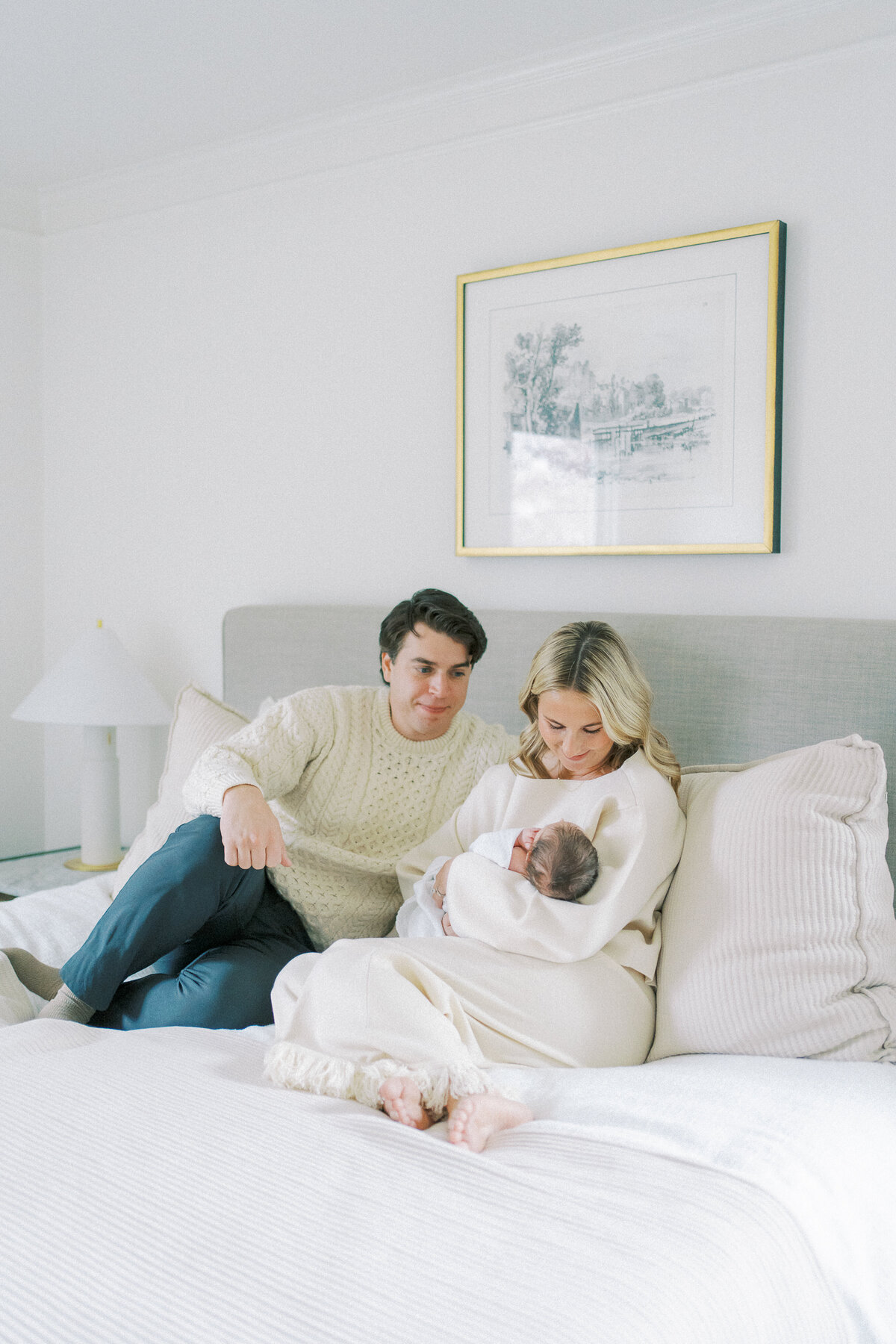 new parents holding baby on their bed