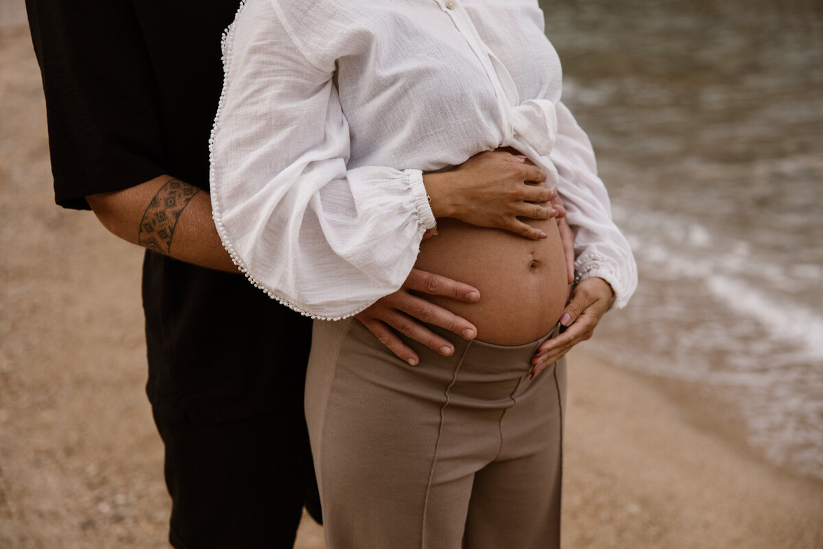 Close up of a man and woman holding pregnant belly during pregnancy photoshoot Ibiza