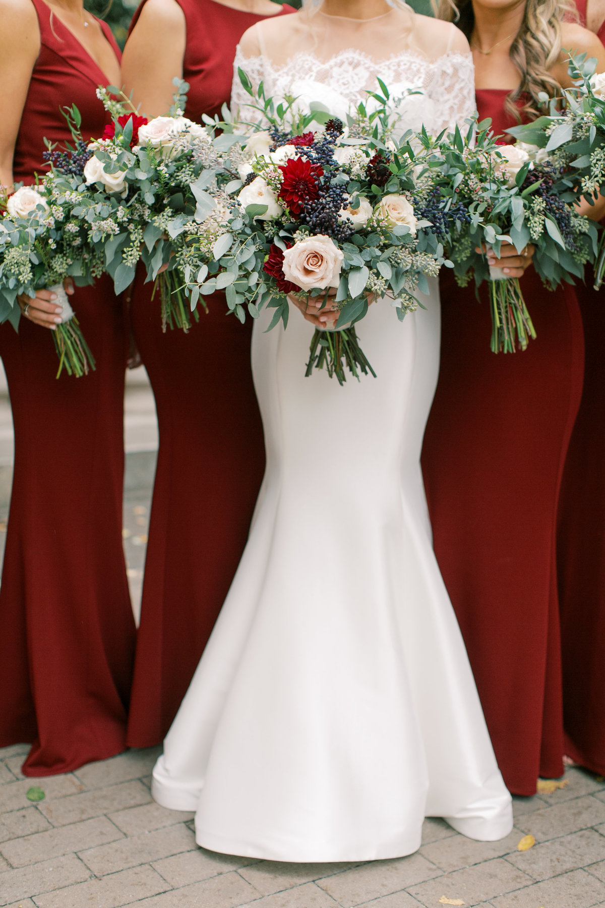 bride wearing strapless wedding gown standing with bridesmaids wearing red dresses holding bouquets