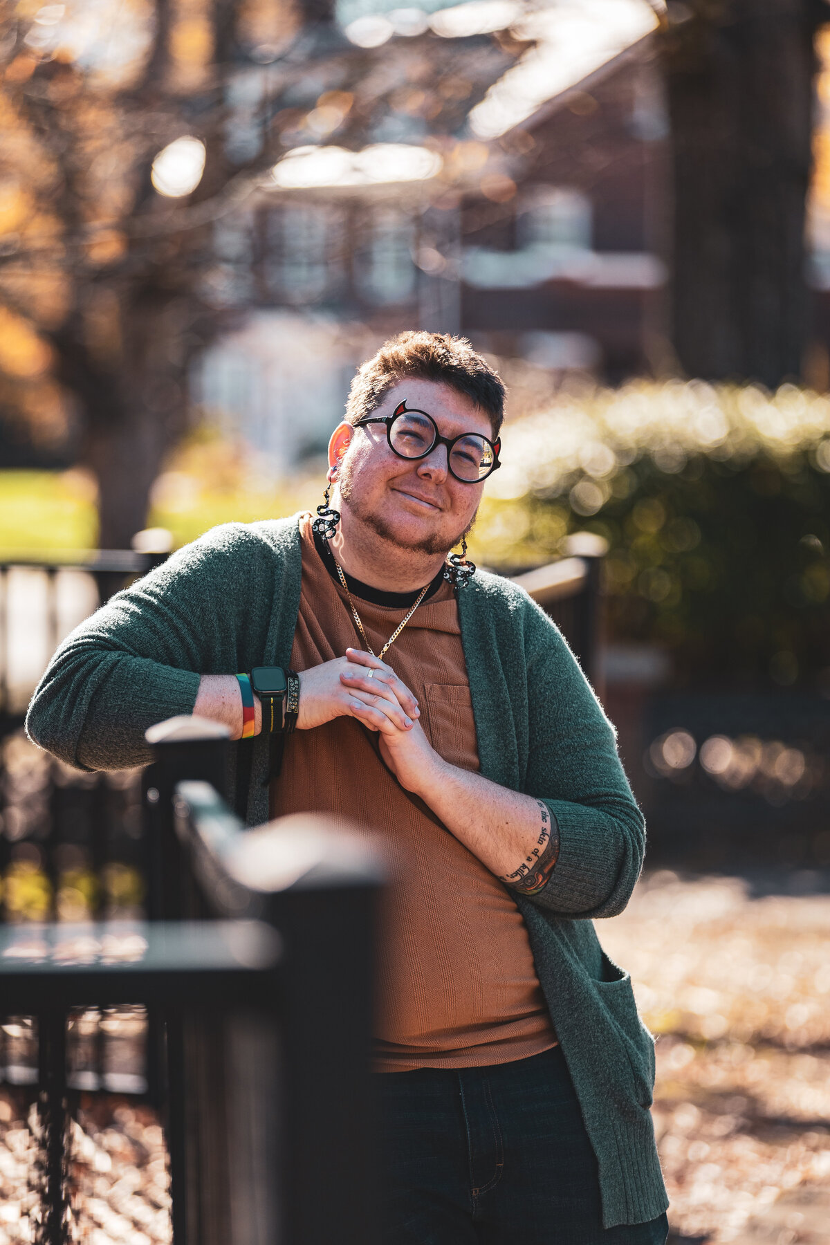 A person leaning against a fence smiling.
