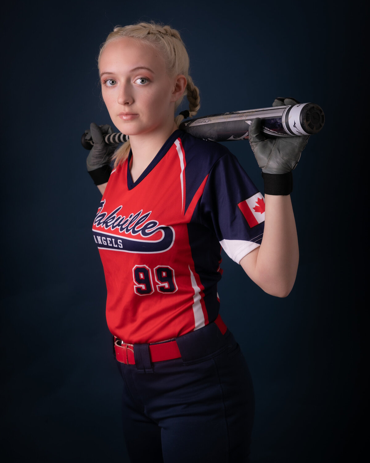Female baseball player holding a bat. 