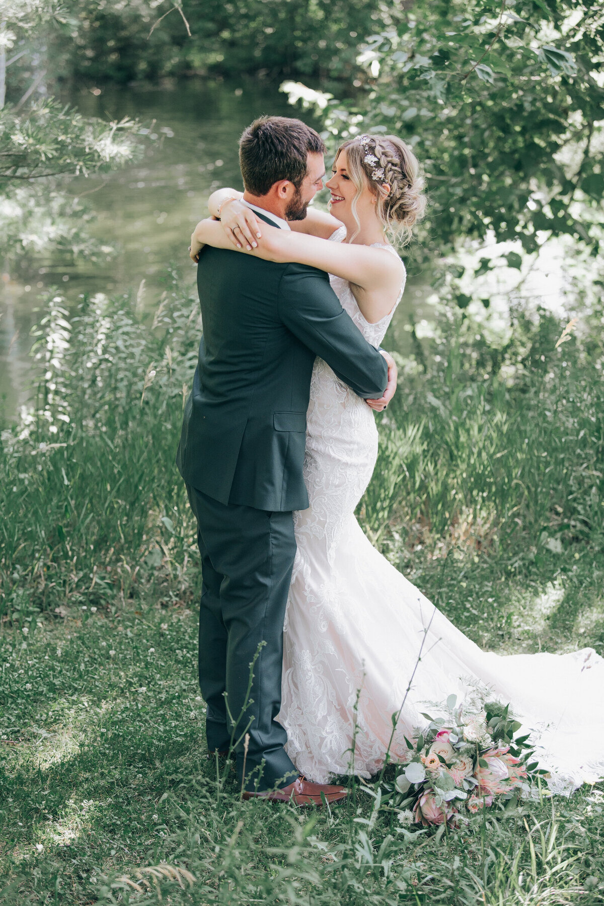 A bride and groom kissing in a forest on their Summer wedding day