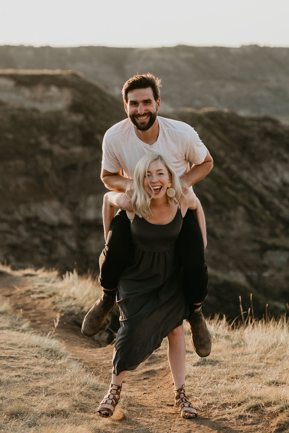 Woman giving man a piggy back captured by Nikki Collette Photography, adventurous and romantic wedding photographer in Red Deer, Alberta. Featured on the Bronte Bride Vendor Guide.