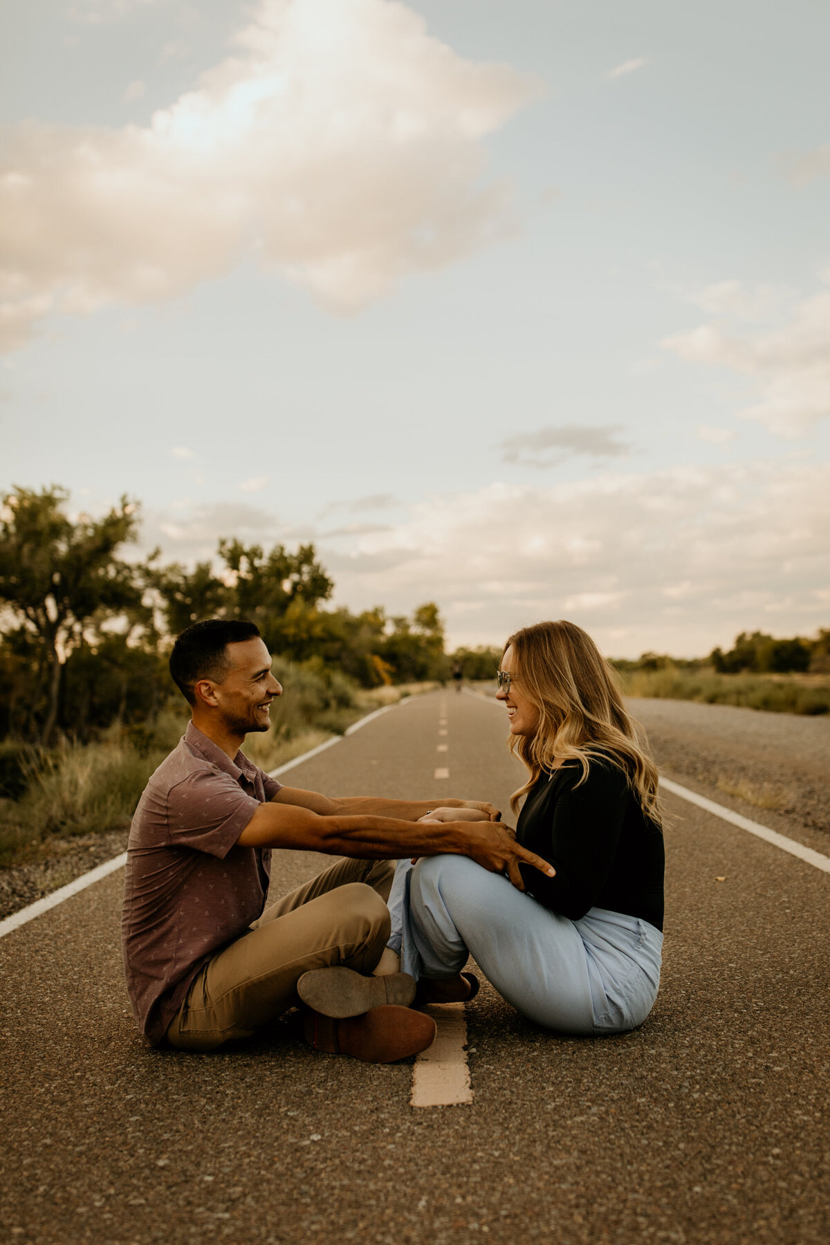 engaged couple sitting on a bike trail in Albuquerque laughing