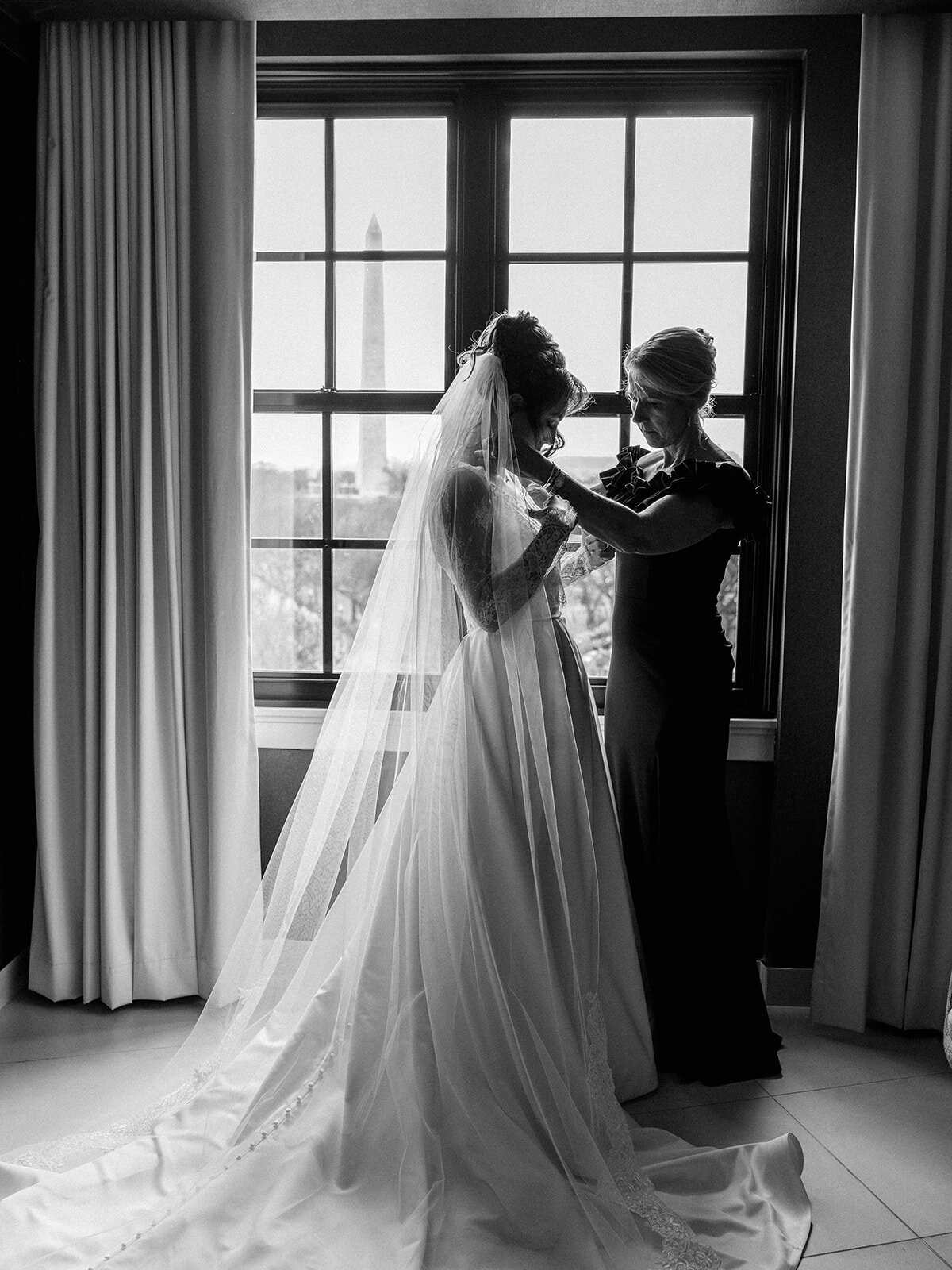 Mom and daughter stand by the bridal suite window at Hotel Washington in DC.
