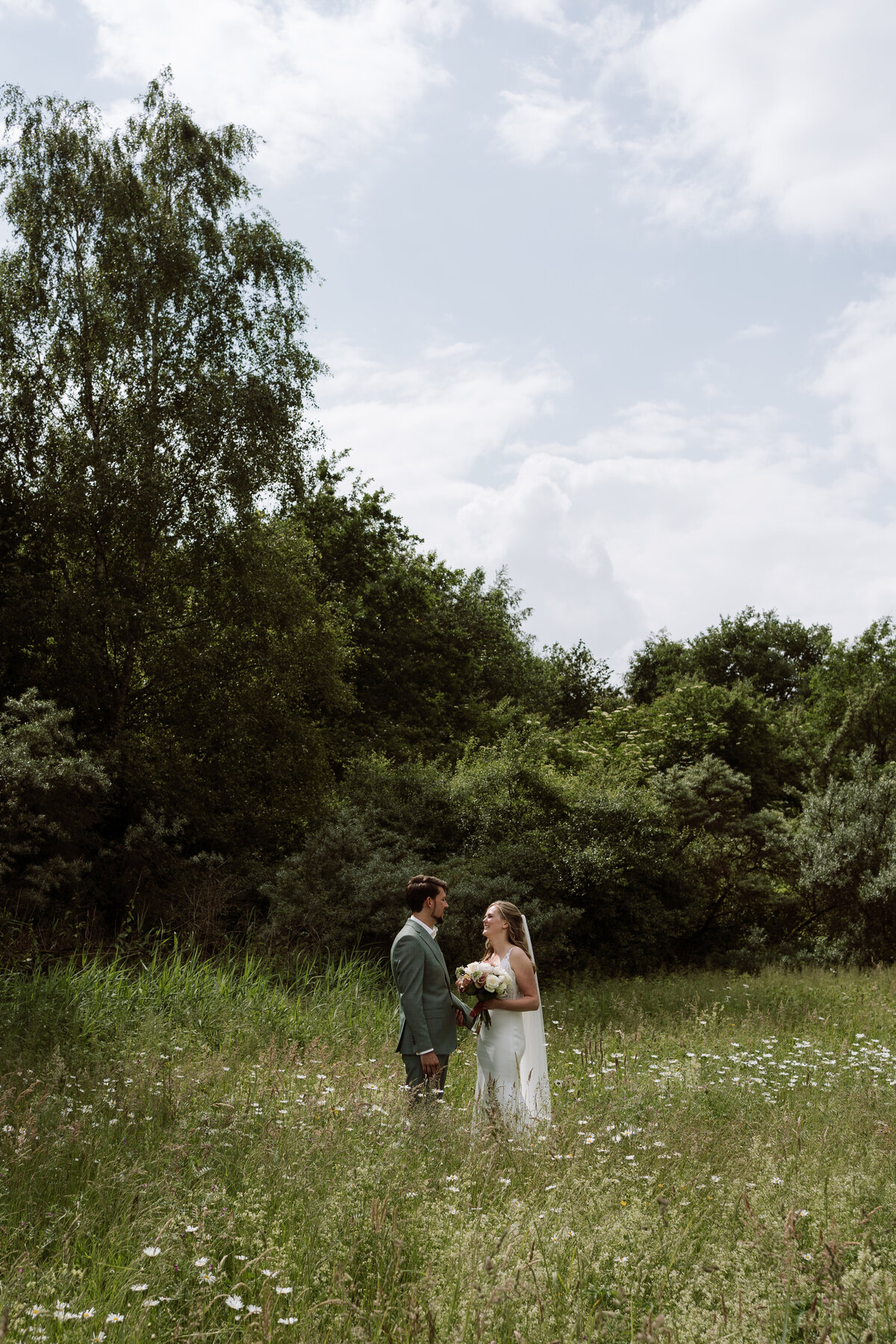Shoot momentje overdag tijdens een bruiloft. Bruidspaar staat in een groen veld. 