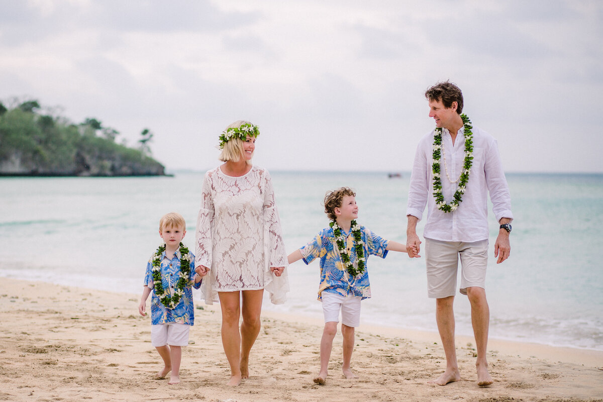 Family with leis walking on a beach