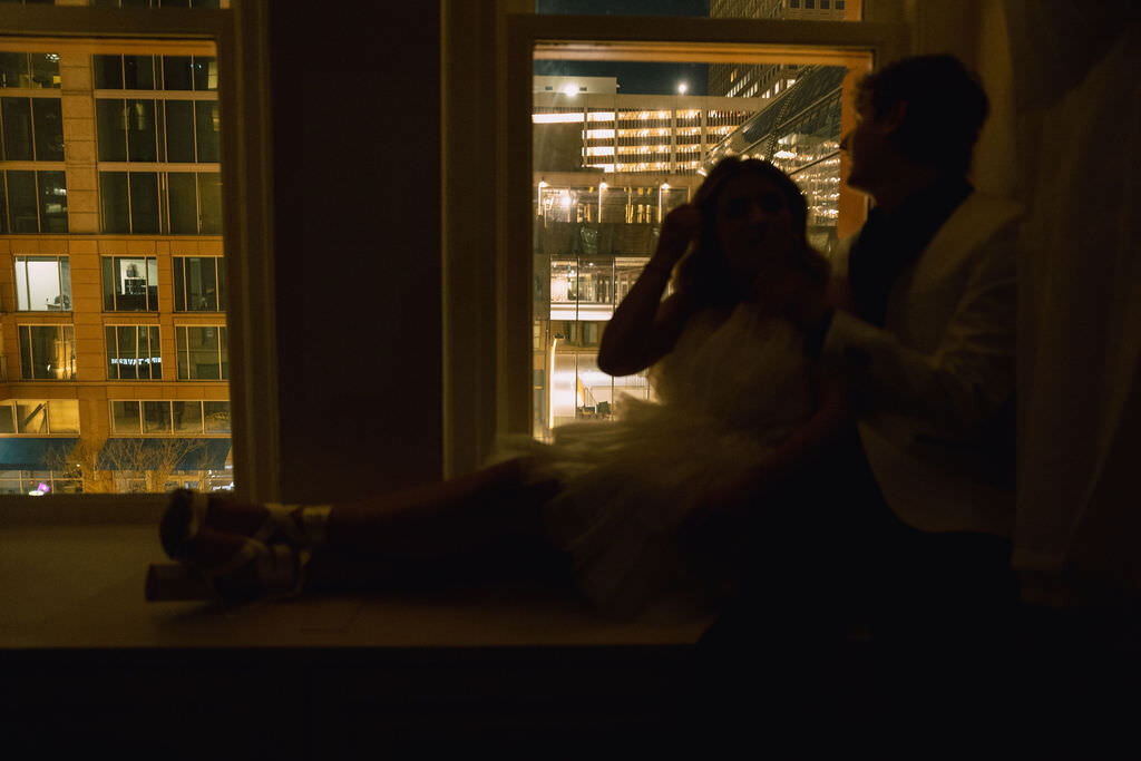 A couple sitting together on a windowsill.