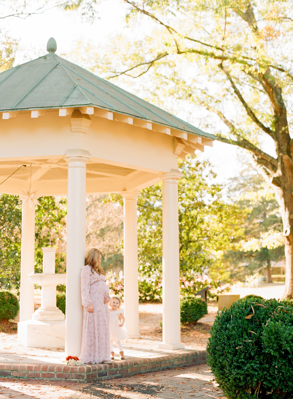 Mom leans against a gazebo and holds her belly. Image by Raleigh maternity photographer A.J. Dunlap Photography.
