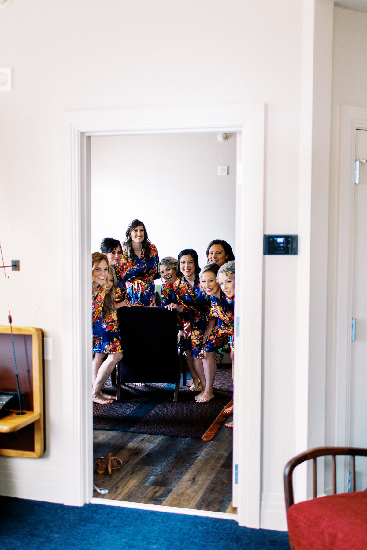 Bridesmaids peaking while bride is putting on her dress in Minneapolis