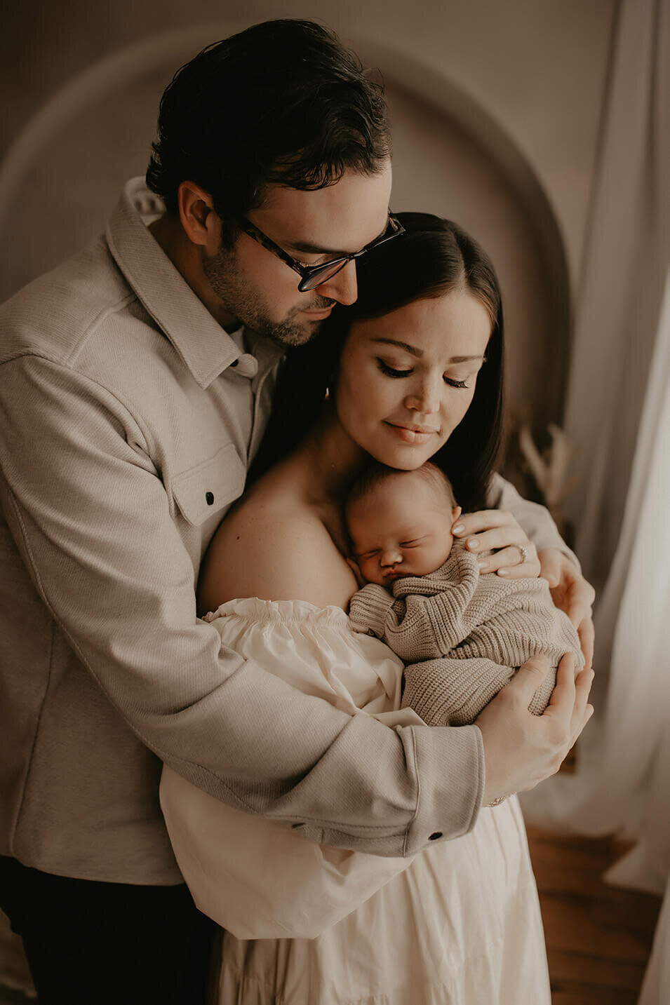 a dad holds his wife and new baby