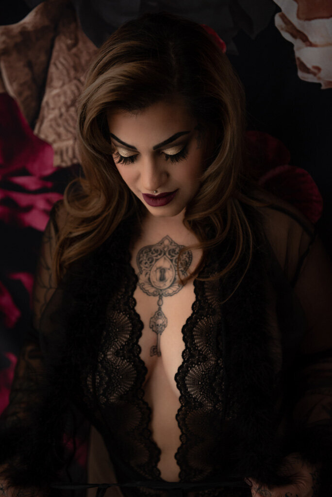 Woman with tattoo wearing lace looking down untying her robe