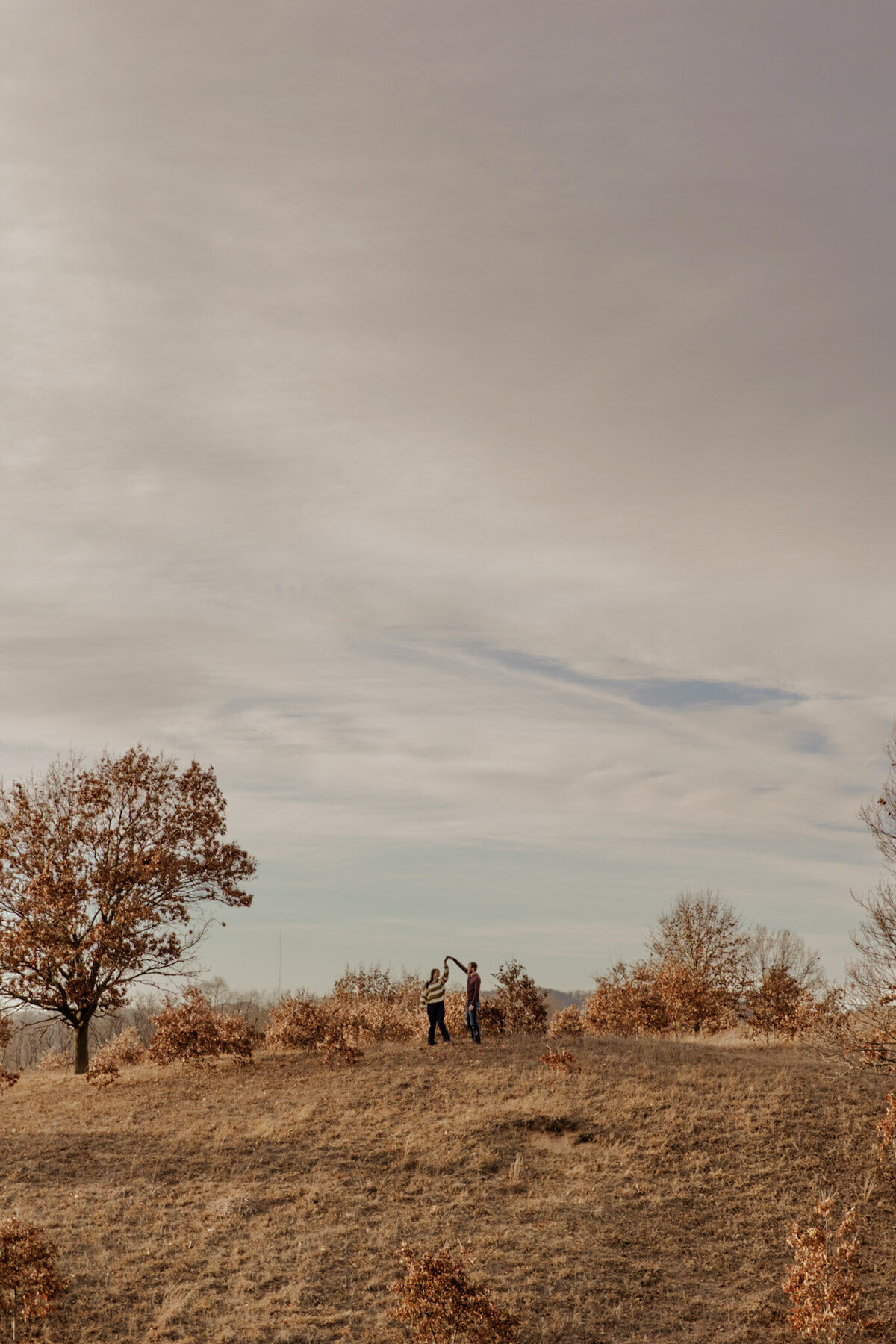 Engaged couple dancing in a field of grass captured by a Minnesota Couples Photographer