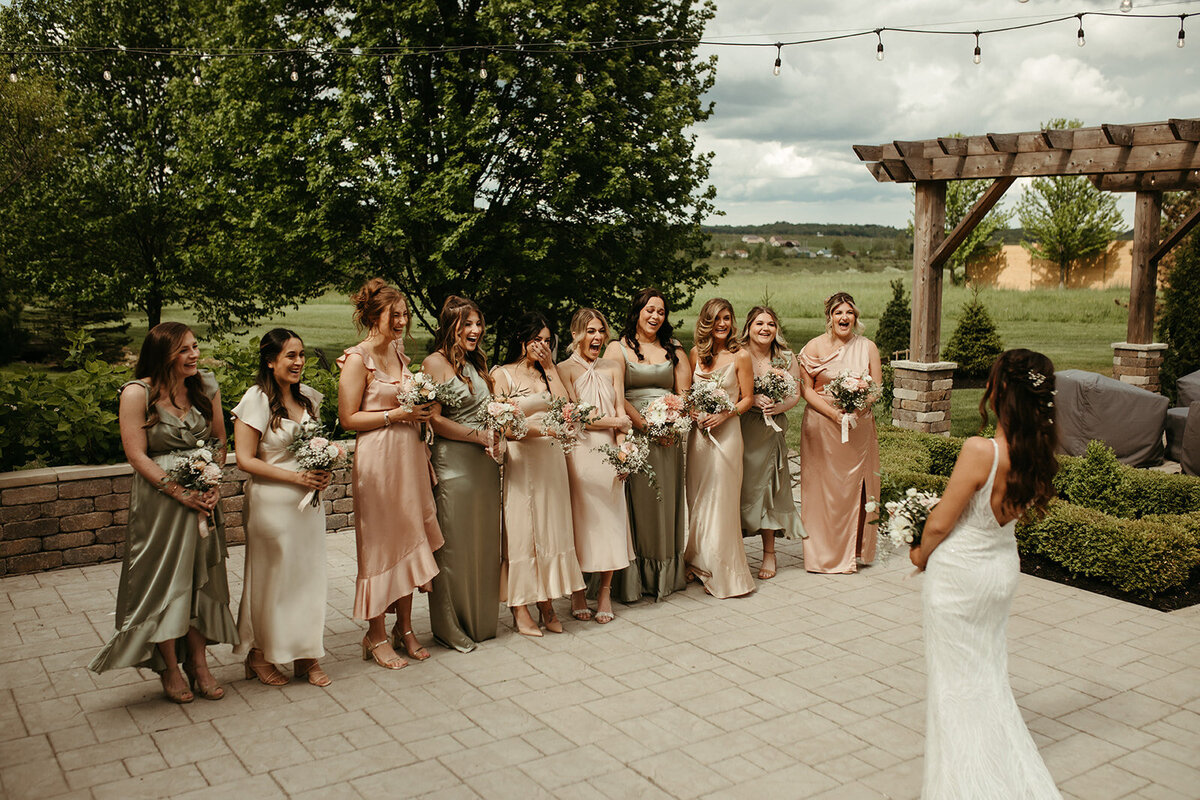 bridesmaids in blush, taupe, and beige dresses with a bride on the stone patio courtyard at Willowbrook wedding venue