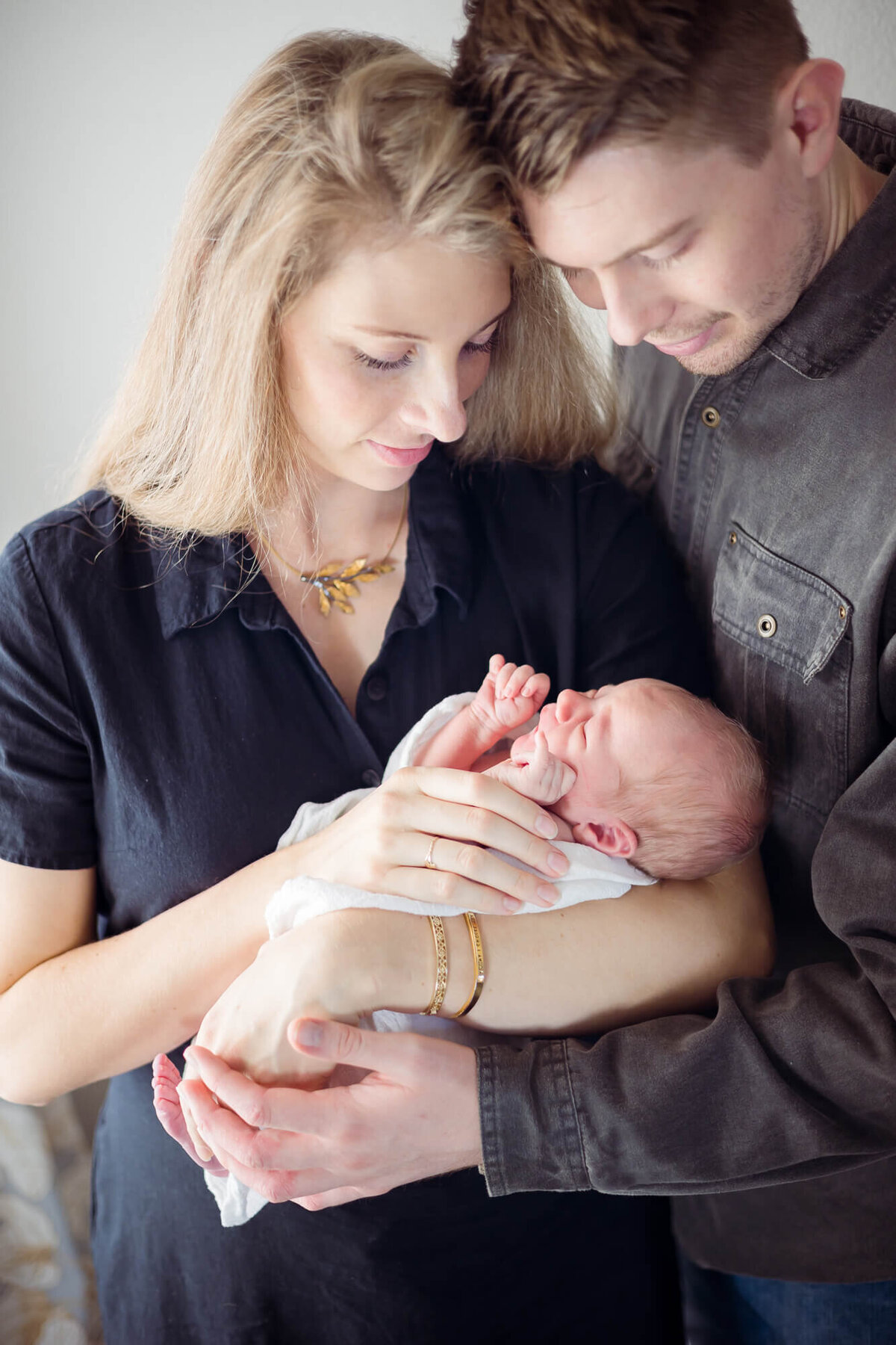 Couple lovingly and gently holding their newborn son during their Las Vegas lifestyl in home newborn session