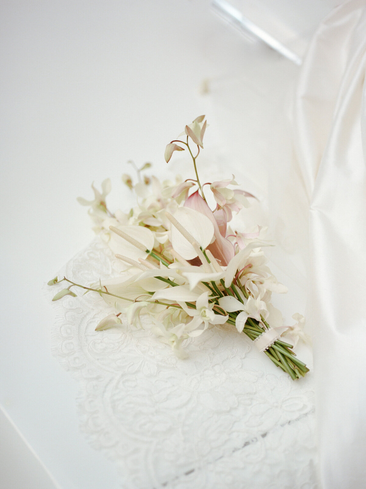 a soft orchid and lily wedding bouquet rests on a lace mantilla veil for a Detroit wedding