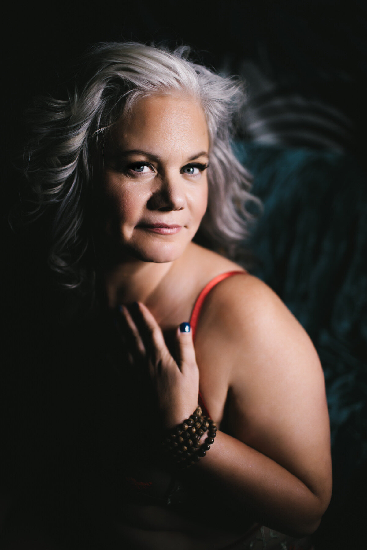 darkly lit boudoir portrait of mature woman smiling