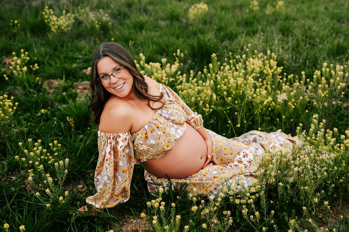 pregnant mom sitting in flower field during Springfield MO maternity photography session