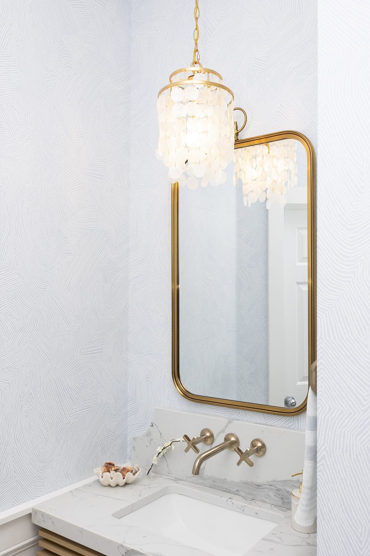 dewine design orlando interior designer contemporary coastal powder bathroom gold framed mirror with bright neutral wallpaper