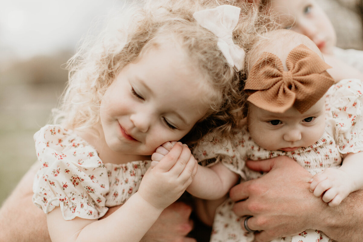 Toddler cuddling tightly to baby.
