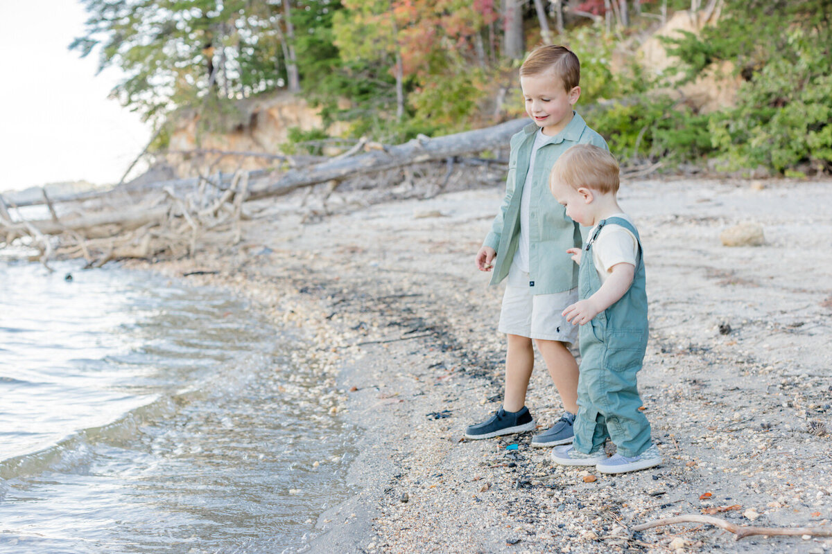 Two brothers stand on a beach on Lake Lanier and look out into the lake as they throw rocks