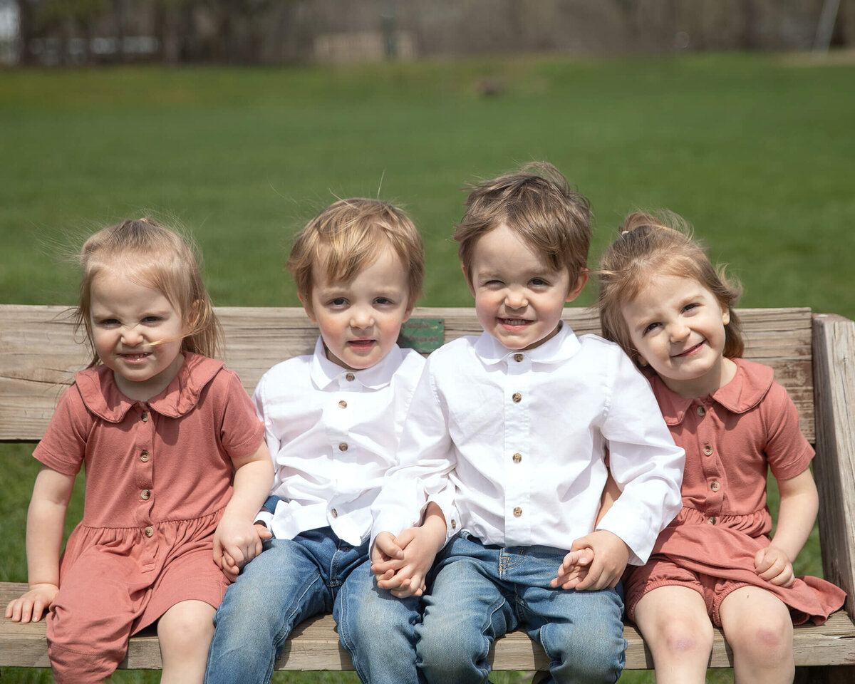 Quadruplets sitting on a park bench.