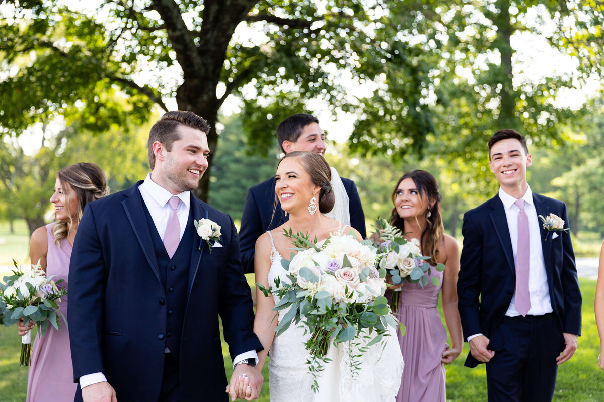 Bride and groom holding hands with bridal party behind them at wedding at Stones River Country Club