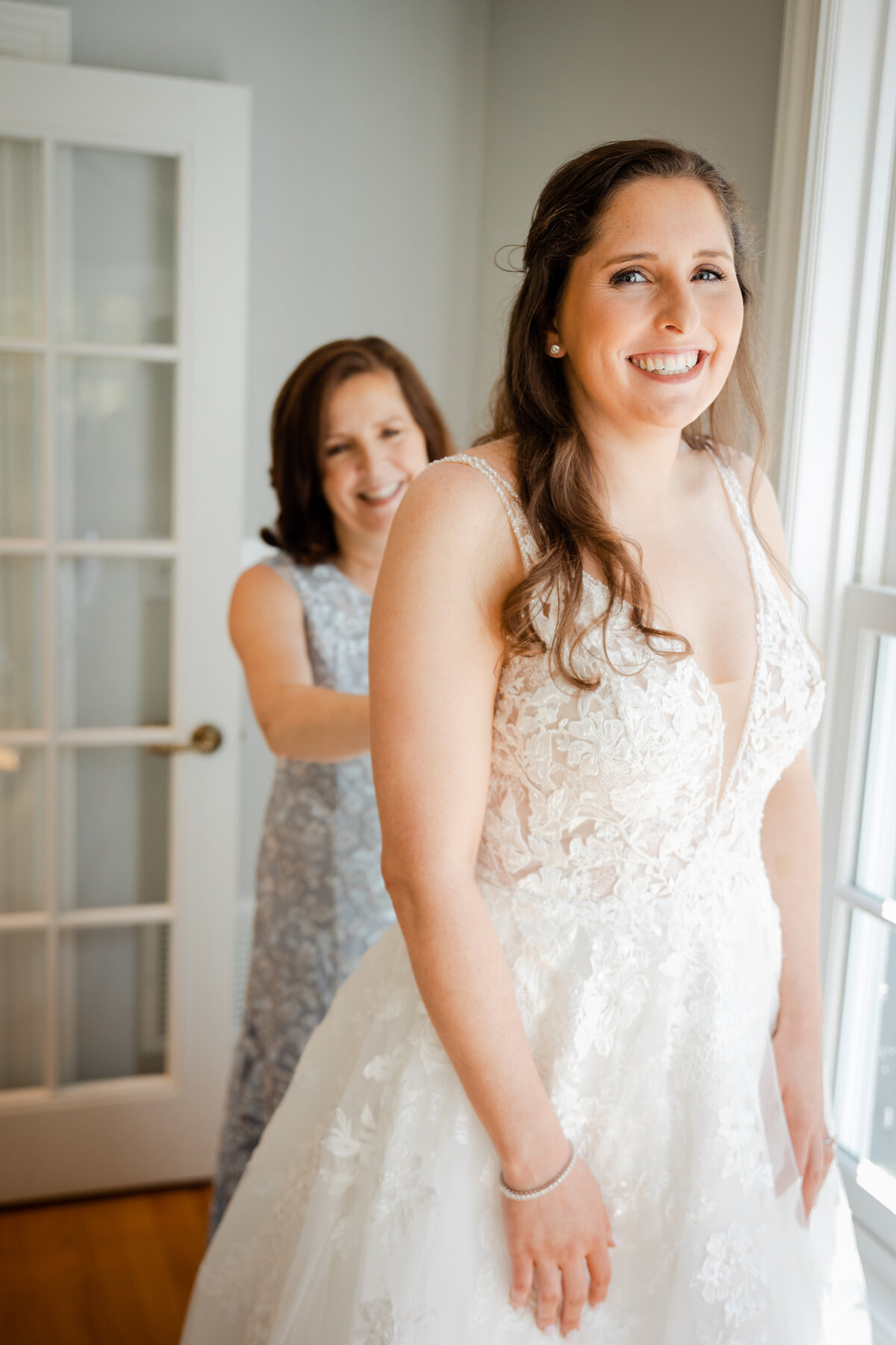 Photograph of a mother helping her daughter into her wedding dress.