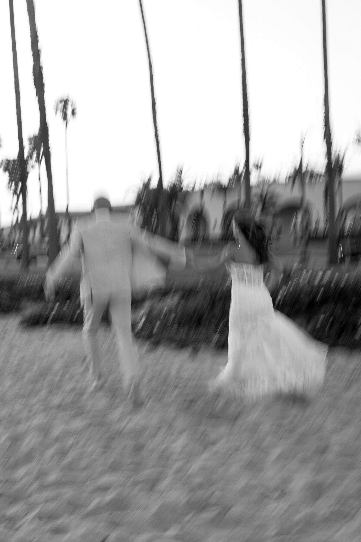 Bride and groom holding hands on beach during sunset at Hilton Beachfront Resort Santa Barbara