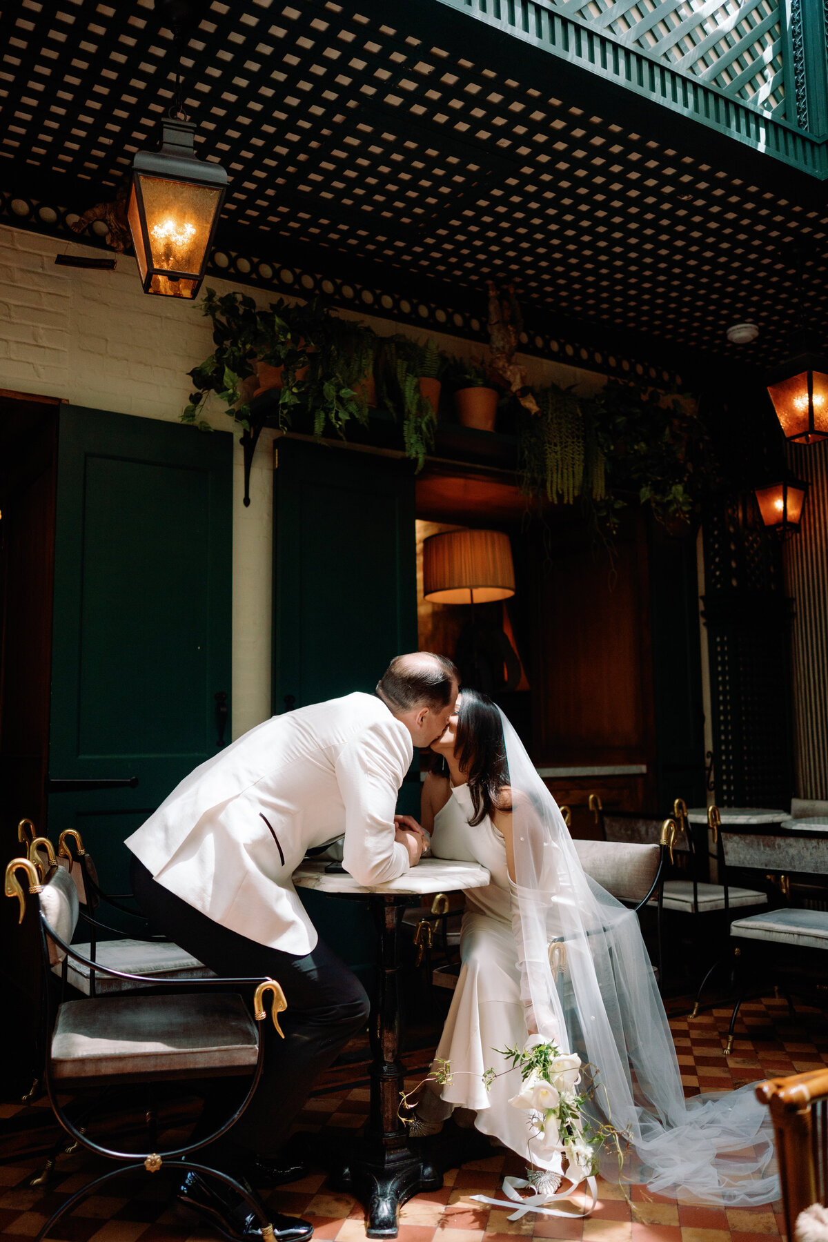 Bride and groom sharing a romantic moment at a café table during their wedding at Hotel Chelsea in New York City.