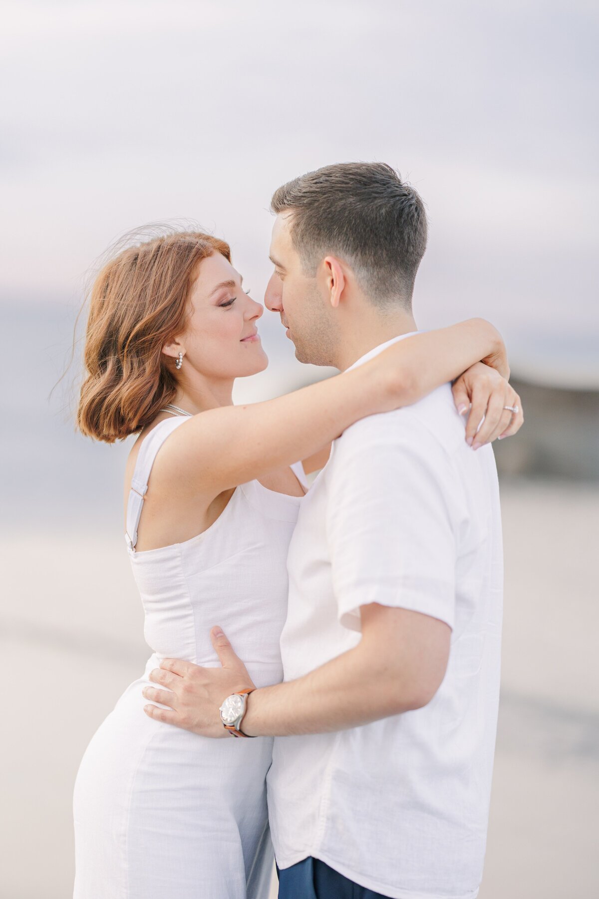 A couple softly smiling during their Wingaersheek Beach engagement pictures.
