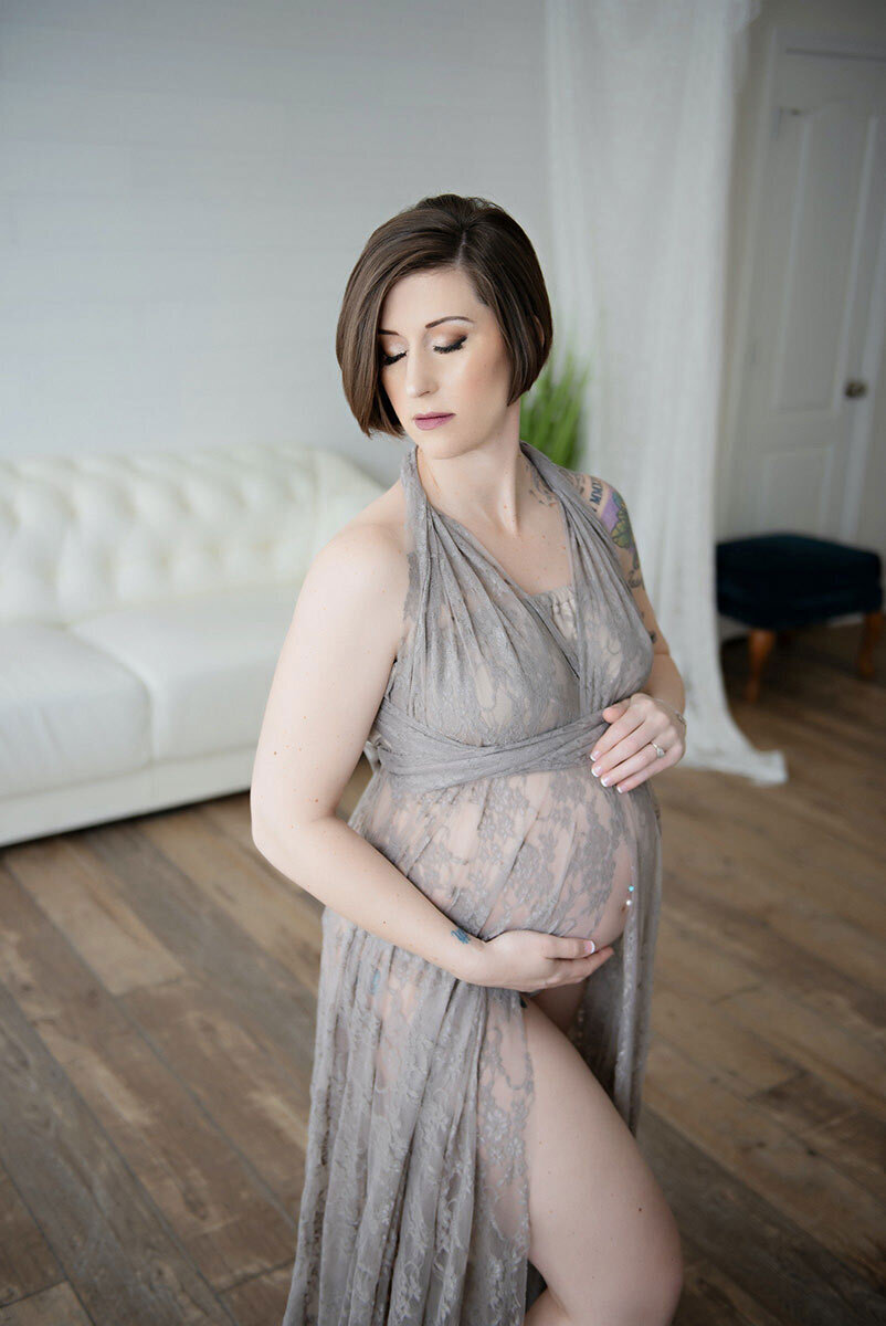 Maternity boudoir photoshoot of woman posing in grey lace